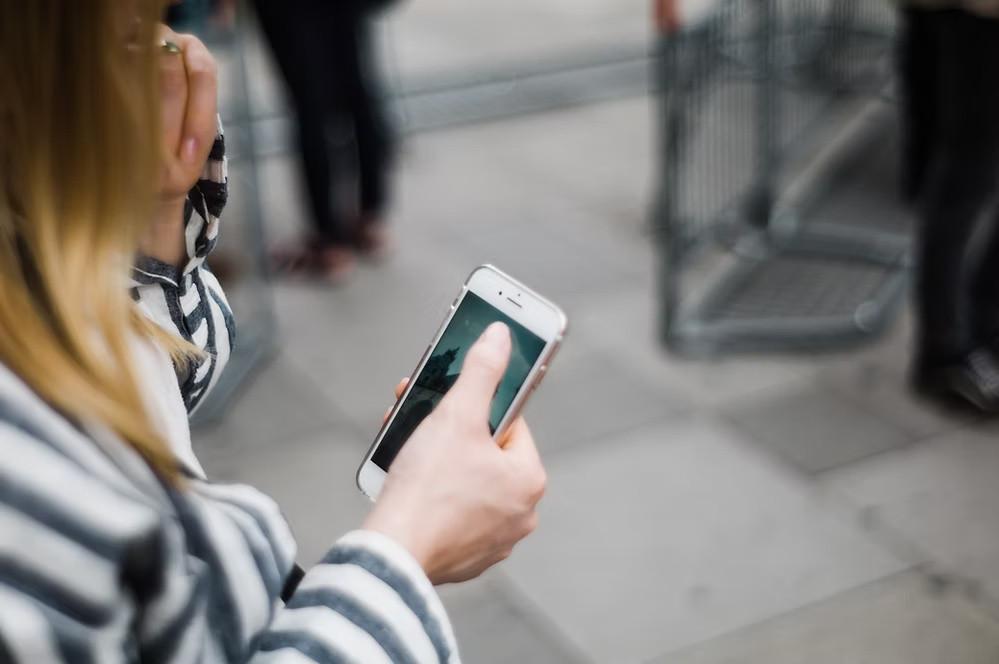 Person holding a smartphone while reviewing or updating social media content outdoors