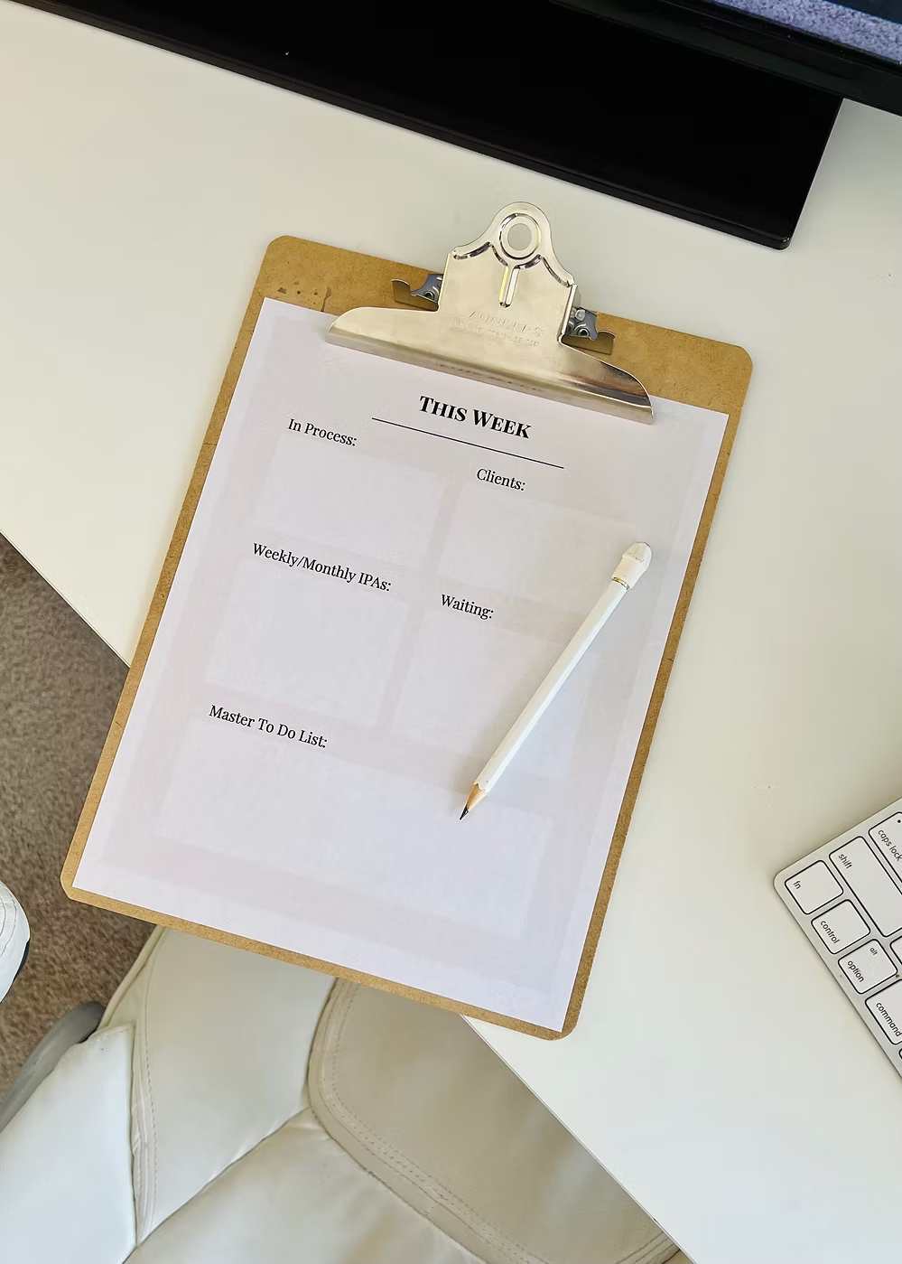 Clipboard with printed weekly planning sheet and pencil resting on a bright office desk.