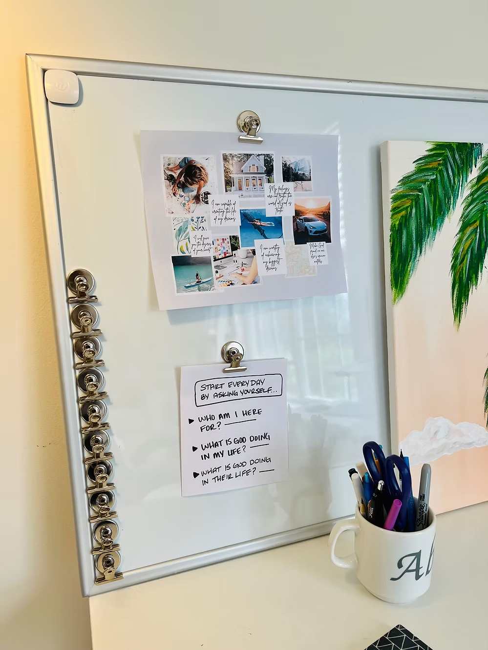 Whiteboard inspiration board with motivational notes, photos, and pens in a mug.
