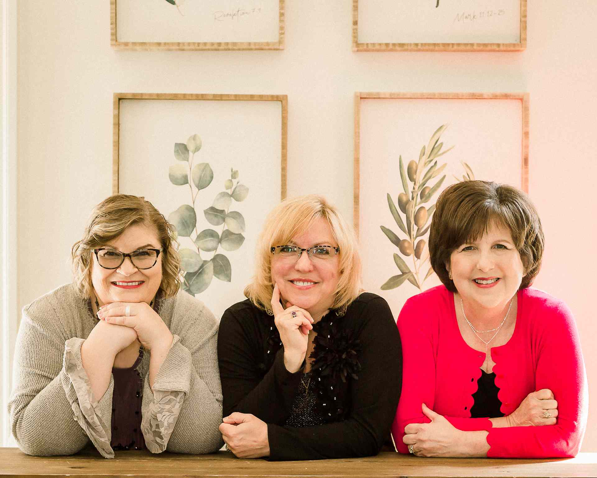Three people smiling at table with botanical prints