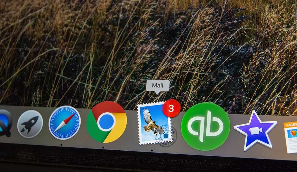 Computer screen showing MacBook dock with mail, Chrome, QuickBooks, and Safari apps.