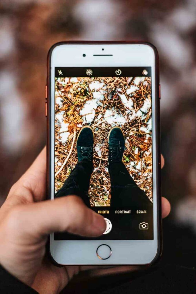 Smartphone screen showing a photo of shoes standing on a ground covered in leaves and snow.