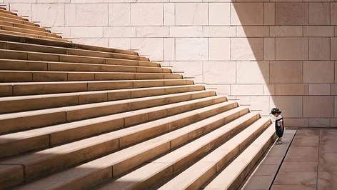 Person walking up modern concrete steps with geometric shadows and clean architectural lines.