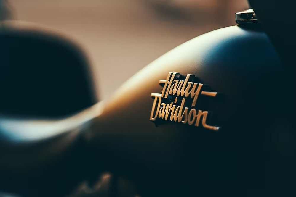 Close-up of Harley Davidson motorcycle logo emblem on black tank with chrome details.