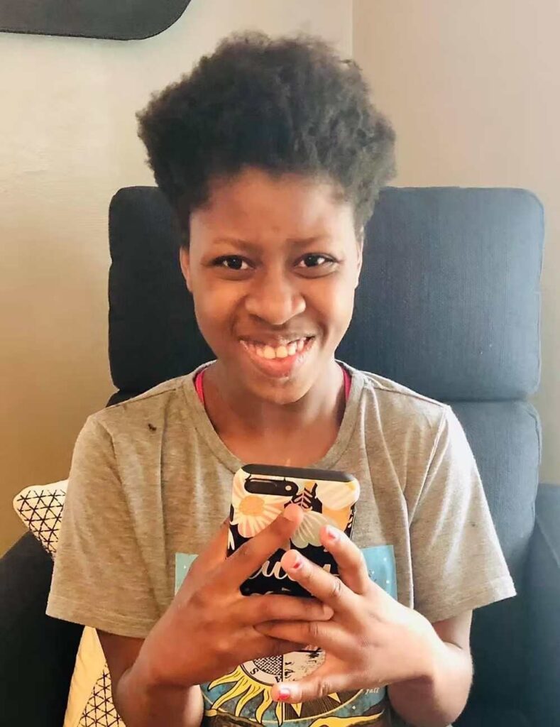Smiling young person sitting in chair holding decorated smartphone with colorful floral case.