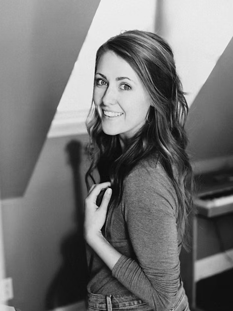 Professional black and white portrait of smiling woman with wavy hair in casual sweater.
