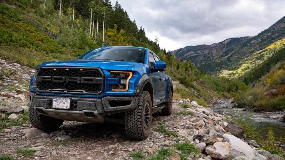 Blue Ford Raptor truck in mountains