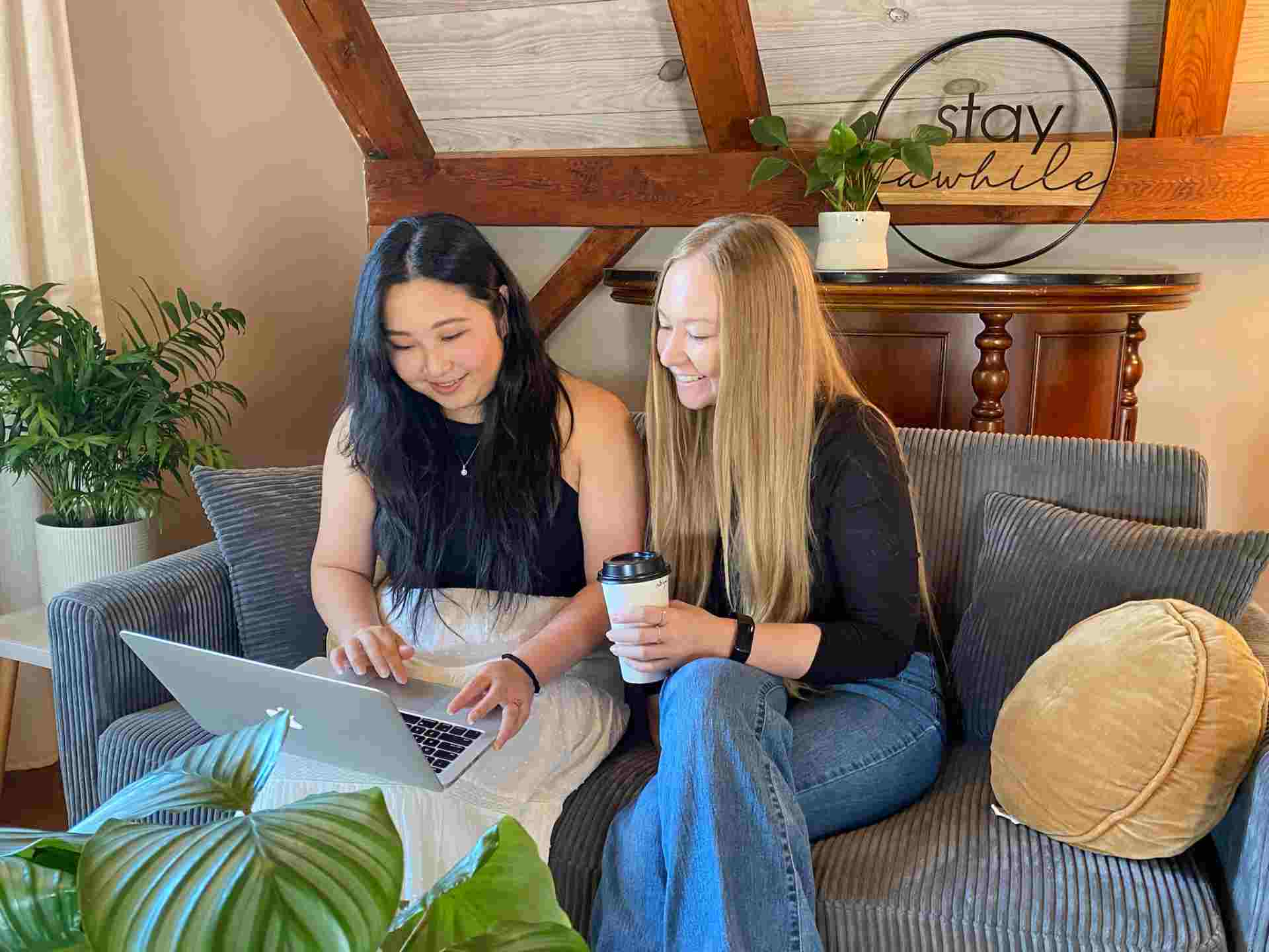 Two people collaborating on laptop with tumbler