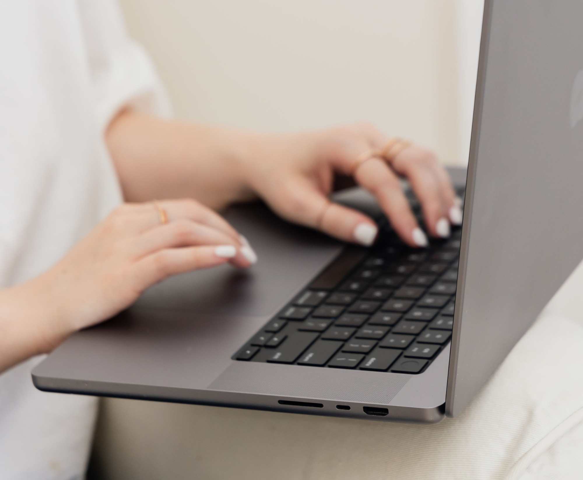Close-up of hands typing on a sleek laptop keyboard.